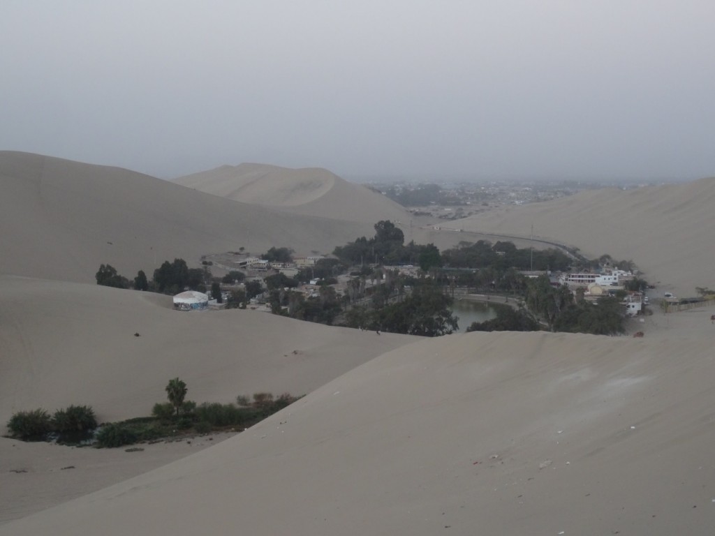 Die Wüstenoase Huacachina mit der Stadt Ica im Hintergrund